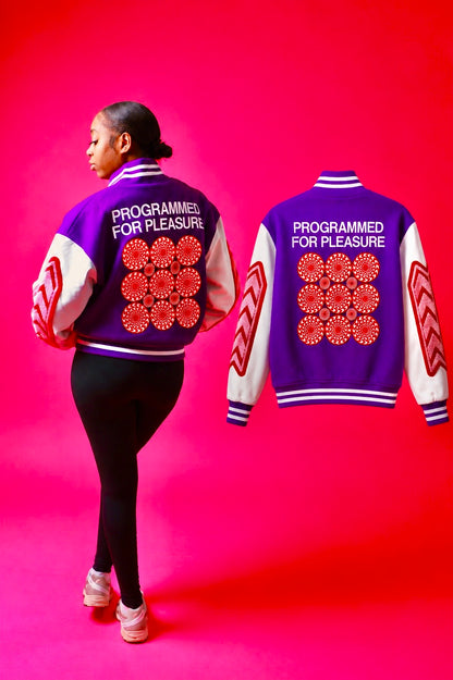 Girl wearing a purple jacket with 'Programmed for Pleasure' text and red floral patterns on a pink background
